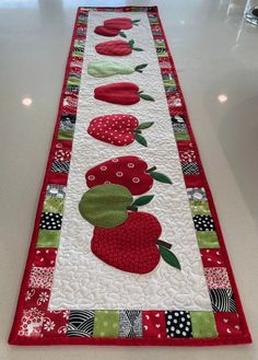 a table runner with red and green fruit designs on the border, along with polka dots