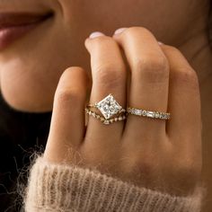 a woman's hand with a diamond ring on her finger and a gold band