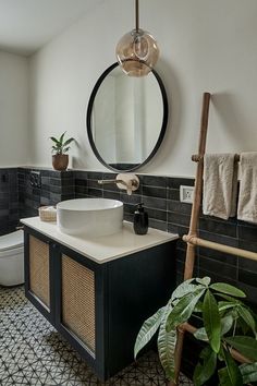 a black and white tiled bathroom with a round mirror