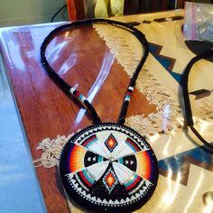 a multicolored necklace on a table next to a pair of eyeglasses