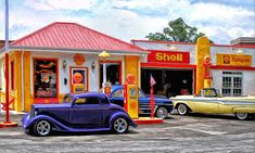 an old fashioned gas station with classic cars parked in front