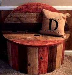 a round wooden bench with a cushion on it's seat and the letter d