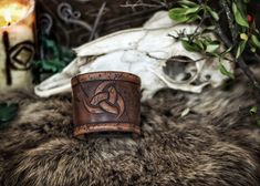 a leather ring sitting on top of a fur covered floor next to a skull and candle