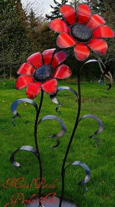 a metal flower sculpture sitting on top of a lush green field