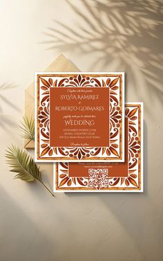 an orange and white wedding card on top of a table next to a palm tree