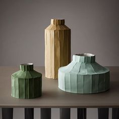 three vases sitting on top of a table next to each other in different colors