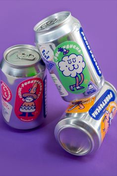 two cans of soda sitting next to each other on a purple surface