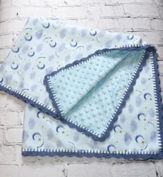 two blue and white cloths on top of each other next to a brick wall