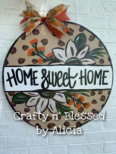 a sign that says home sweet home on the side of a building with flowers and leaves painted on it