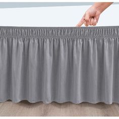 a person is pointing at the top of a bed skirt with pleated edges on it