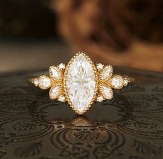 a close up of a diamond ring on top of a black surface with an ornate design