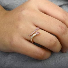 a woman's hand with a pink and white diamond ring on her left hand