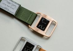 two electronic watches sitting next to each other on top of a white table with green straps