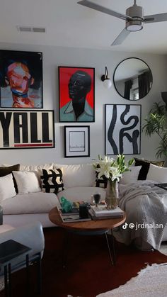 a living room filled with white furniture and pictures on the wall above it's coffee table