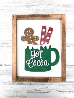 a wooden frame with some paper cutouts on it and a green mug filled with hot cocoa