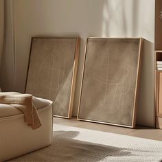 two framed art pieces sitting next to each other on the floor in front of a window