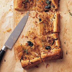 a piece of bread with olives on it next to a knife