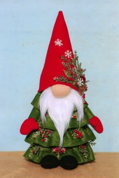 a small christmas tree with a gnome on it's head and snowflakes