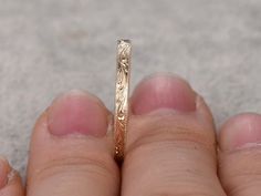 a close up of a person's hand holding a wedding ring