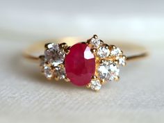 a gold ring with a red stone surrounded by white stones