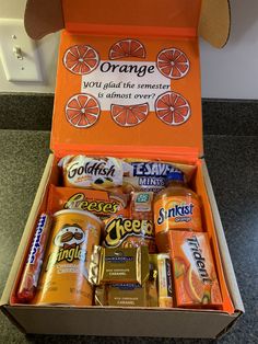 an orange box filled with lots of different types of drinks and candy bar wrappers