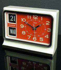 a red and white clock sitting on top of a table