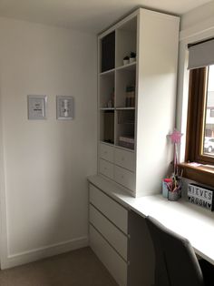 an empty room with white cabinets and desk in front of a large window on the wall