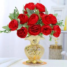 a gold vase filled with red roses on top of a table