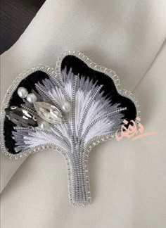 a white and black brooch with pearls on it's center piece is shown