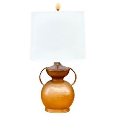 a lamp that is on top of a table with a white shade over the base