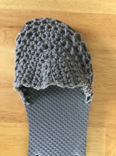 a crocheted gray slipper on top of a wooden floor