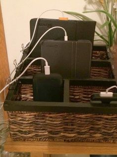 a wicker basket with some electronics in it on a table next to a vase