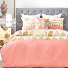 a bed with pink and gold comforters in a bedroom next to two nightstands