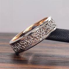 two gold wedding bands with celtic designs on the inside, sitting on a wooden surface