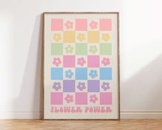 a colorful poster with flowers on it in front of a white wall and wooden floor