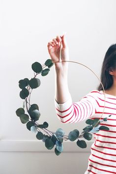 a woman holding up a hoop with leaves on it