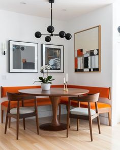 a dinning room table with two chairs and an orange bench in front of it