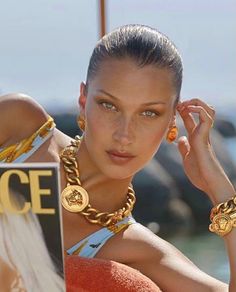 a woman wearing gold jewelry and holding a sign