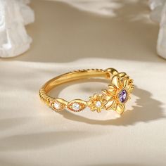 The ring is like a blossoming golden flower, the main stone is translucent and bright, emitting a mysterious purple glow. The gold-colored body of the ring seems to be delicately entwined with petals, like a flower in bloom, radiating warmth and splendor. The sterling silver texture of the ring is light and pure, as if to give it a noble and dignified. Wearing this ring, you can feel the scent of flowers, warmth and beauty. Let it witness every precious moment in your life and bring you happines Delicate Gold Flower Ring With Gemstone, Elegant Purple Flower Ring, Elegant Purple Flower Wedding Ring, Gold Flower Ring With Birthstone For Promise, Gold Flower Ring With Birthstone For Wedding, Gold Flower-shaped Gemstone Jewelry, Gold Amethyst Open Ring Fine Jewelry, Gold Flower Shaped Jewelry With Gemstone, Gold Flower Gemstone Jewelry