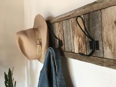 a hat and jacket hang on a wooden coat rack next to a potted plant