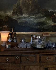 there is a painting on the wall next to a dresser with glasses and cups on it