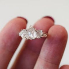 three stone ring sitting on top of someone's finger in front of the camera