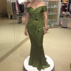 a woman standing in front of a mirror wearing a green dress