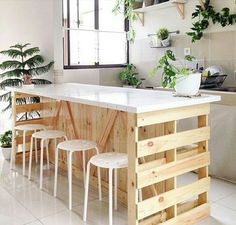 a kitchen island made out of pallet wood with stools and plants on it