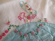 an embroidered piece of cloth with pink flowers on it