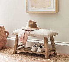 a hat, scarf and shoes are on a bench in front of a framed painting