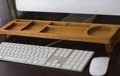 a keyboard and mouse on a desk with a wooden tray attached to the computer monitor