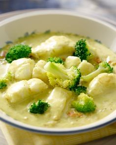 a bowl filled with broccoli and dumplings on top of a yellow napkin