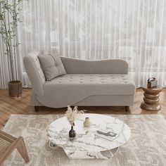 a living room with a couch, coffee table and vases on the floor in front of a curtained window