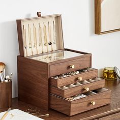 an open wooden jewelry box sitting on top of a desk